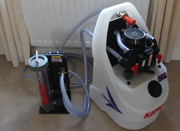 Technician using specialized equipment for power flushing a heating system, highlighting power flushes service in London by We Fix Plumbing London.
