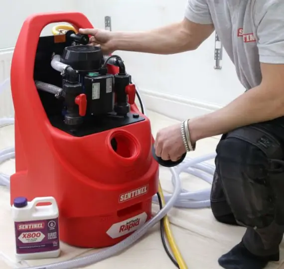 Technician performing a power flush on a central heating system, highlighting power flushes service in London by We Fix Plumbing London.