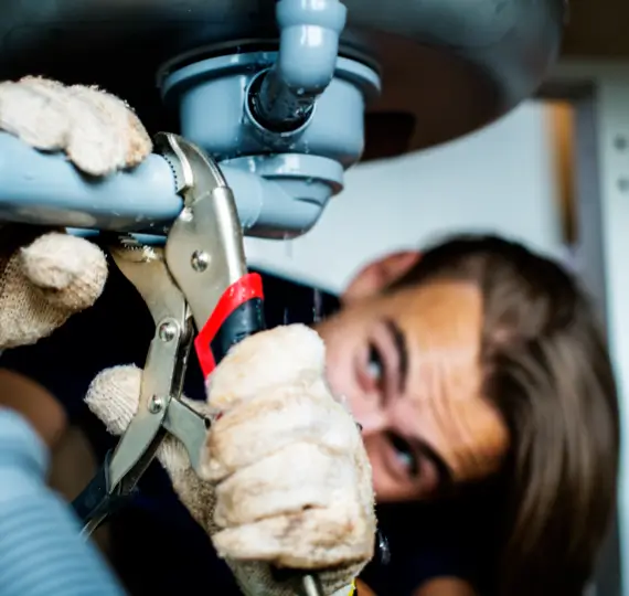 man-fixing-kitchen-sink Plumber fixing a kitchen sink, addressing hidden plumbing leaks in a London home.